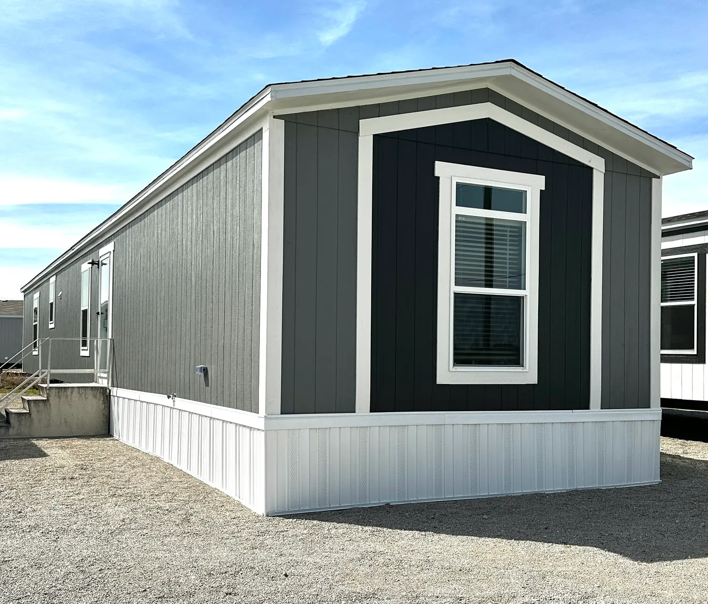 Beautiful 3 bedroom, 2 bathroom manufactured home featuring a modern charcoal interior and open-concept design. The stylish kitchen includes stainless steel appliances, a stainless steel farmhouse sink, and ample cabinet space. The spacious living room offers a built-in entertainment center with electric fireplace, perfect for relaxing or entertaining. The private primary suite features a tiled low-profile walk-in shower, a large garden soaking tub, and generous storage. This home combines affor