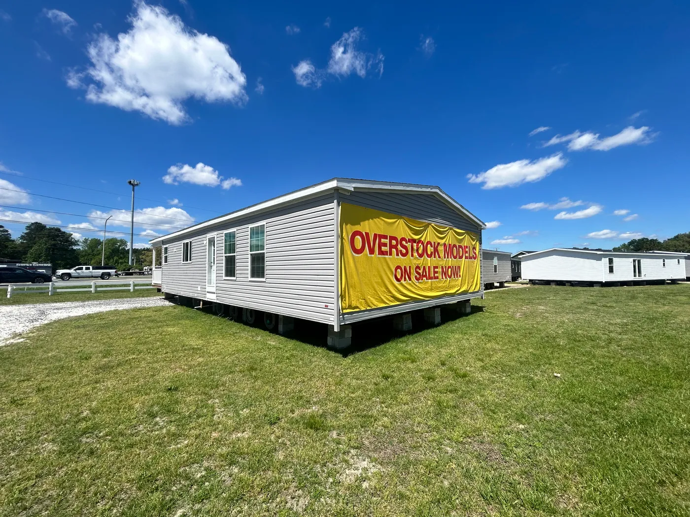 Rear view of the home. Sign featured "OVERSTOCKED MODELS ON SALE NOW" 