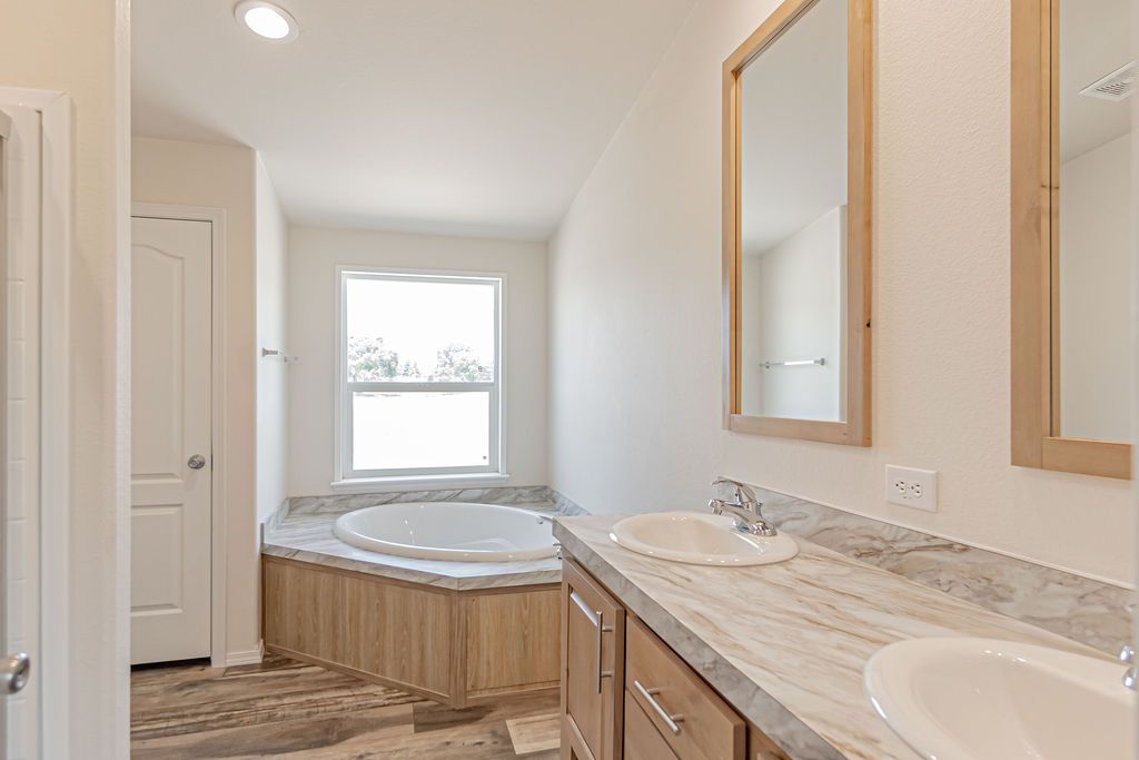 Unwind in a luxurious primary bathroom designed as a private retreat. The space features a large soaking tub that serves as a stunning focal point, perfect for relaxation after a long day. Generously sized and thoughtfully laid out, the bathroom offers plenty of room for movement and storage while maintaining a calm, spa-like atmosphere. Soft lighting and open space enhance the sense of comfort and elegance, making this primary bath an inviting haven that blends everyday functionality with refin