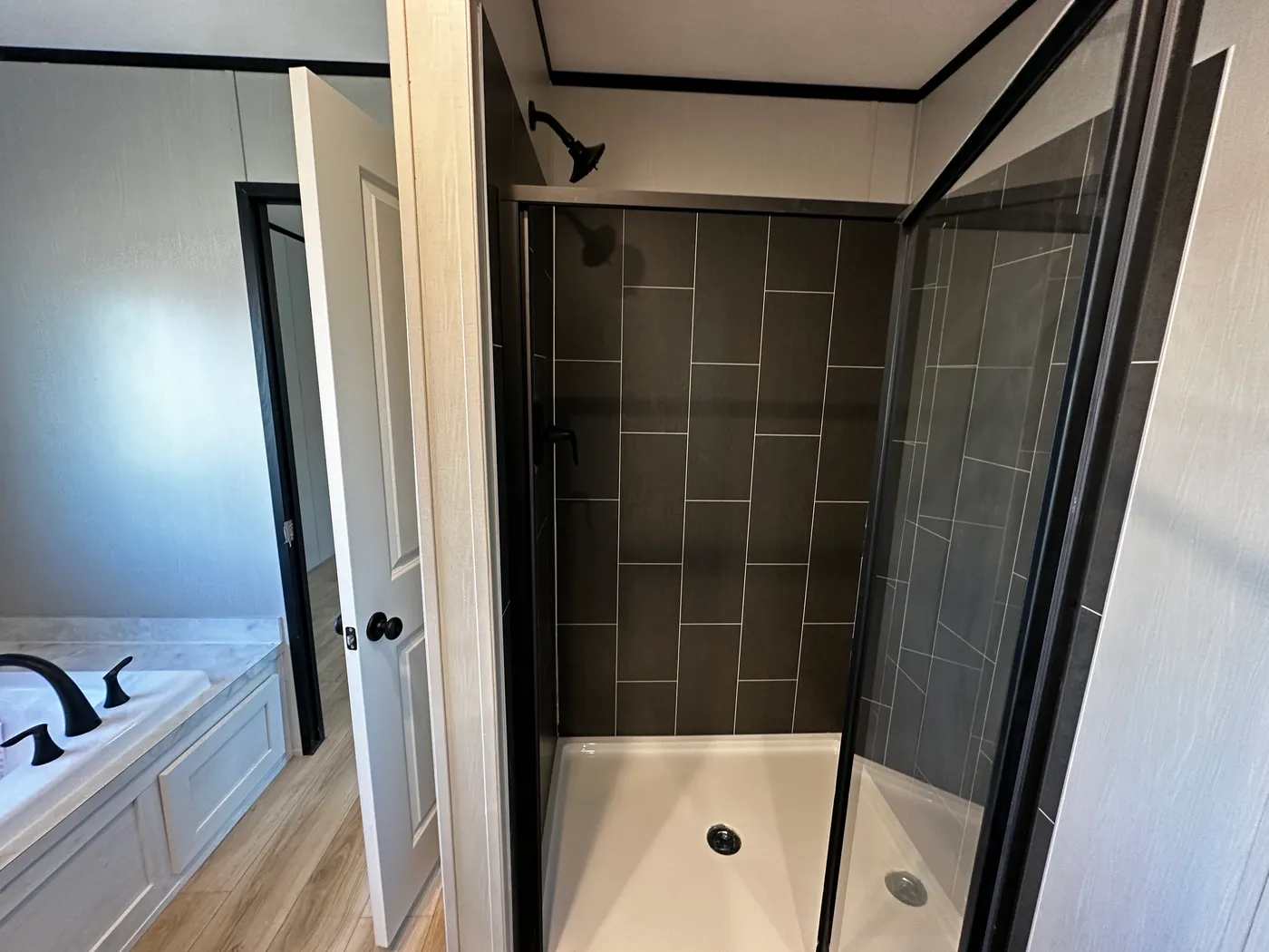 Beautiful 3 bedroom, 2 bathroom manufactured home featuring a modern charcoal interior and open-concept design. The stylish kitchen includes stainless steel appliances, a stainless steel farmhouse sink, and ample cabinet space. The spacious living room offers a built-in entertainment center with electric fireplace, perfect for relaxing or entertaining. The private primary suite features a tiled low-profile walk-in shower, a large garden soaking tub, and generous storage. This home combines affor