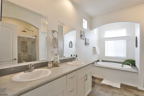 Generous master bath includes his and her sinks, ceramic tile shower, and garden tub