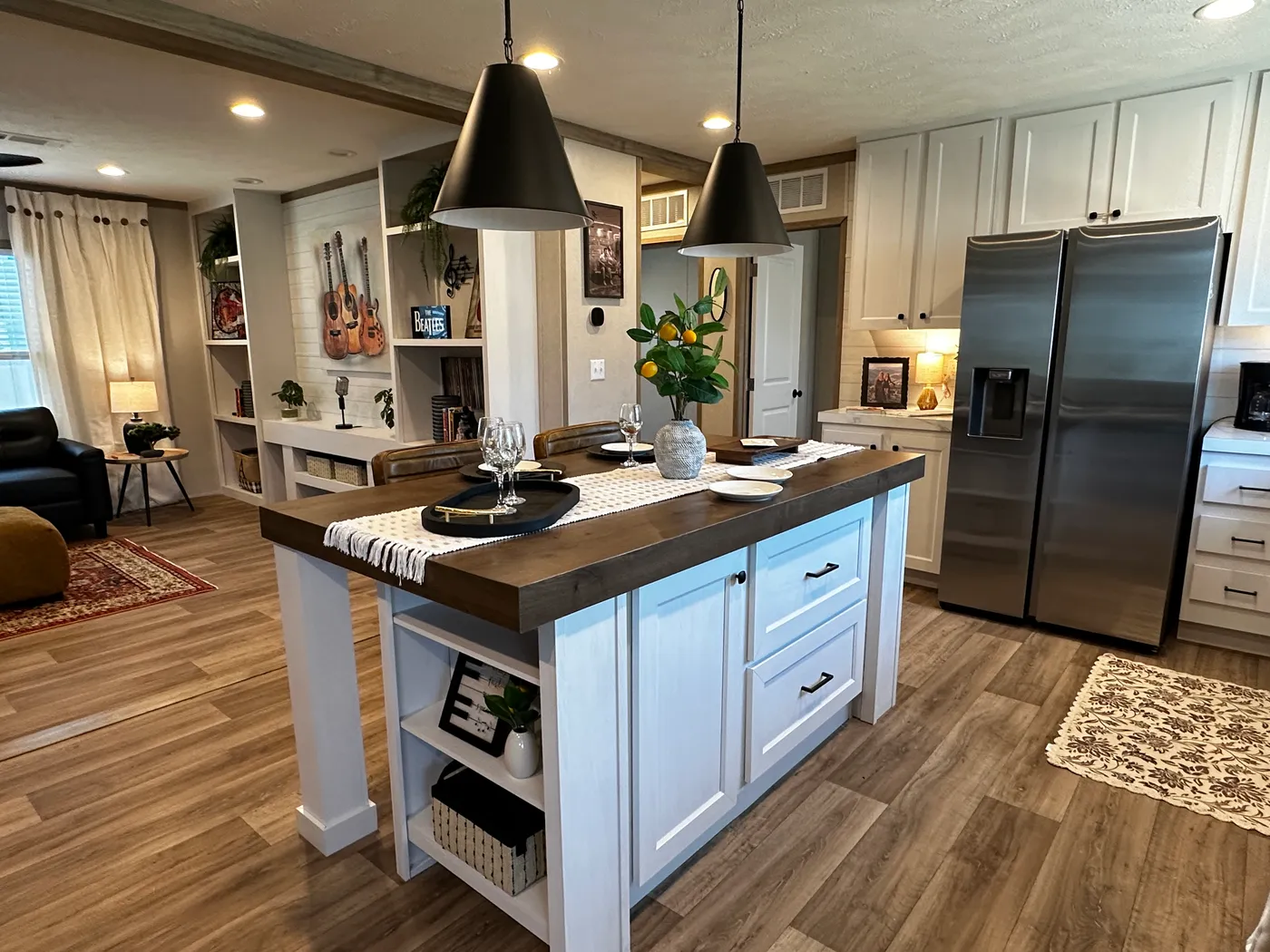 Modern luxury meets affordability in this 3 bedroom, 2 bathroom double wide manufactured home designed for comfort and style. The open-concept layout features a spacious living area with a gorgeous built-in entertainment center and plenty of natural light. The designer kitchen includes stainless steel appliances, a large kitchen island, and ample cabinet space, perfect for cooking and entertaining. Enjoy enhanced comfort with energy-efficient upflow ceiling vents for improved airflow throughout 