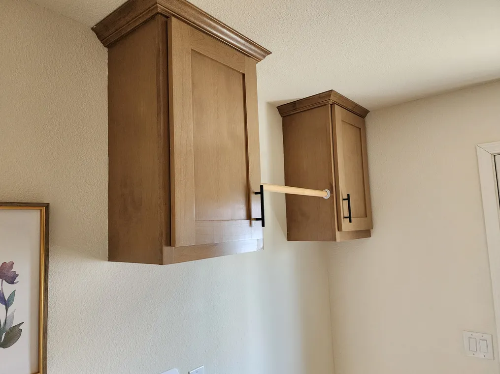 Cabinets & pole over washer & dryer area