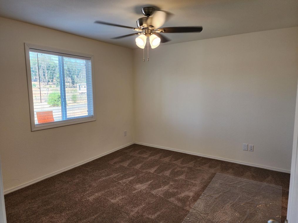 Primary bedroom has ceiling fan, walk-in closet and window to the front yard.