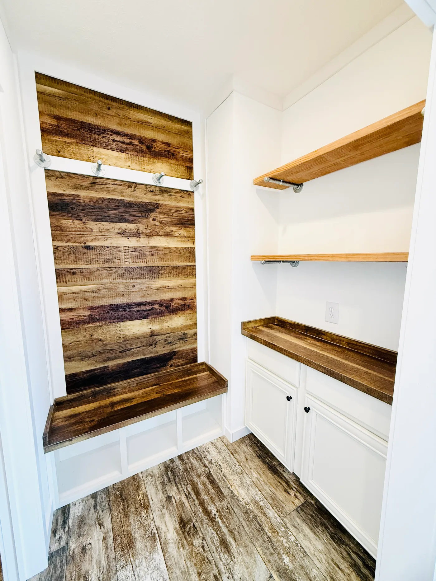 This functional space provides the perfect drop zone for everyday living. Featuring built-in cabinetry, open shelving, and a rustic wood accent bench with hooks, it offers plenty of storage for shoes, bags, and coats. Designed with both style and convenience in mind, this space helps keep the home organized while adding charming farmhouse character.