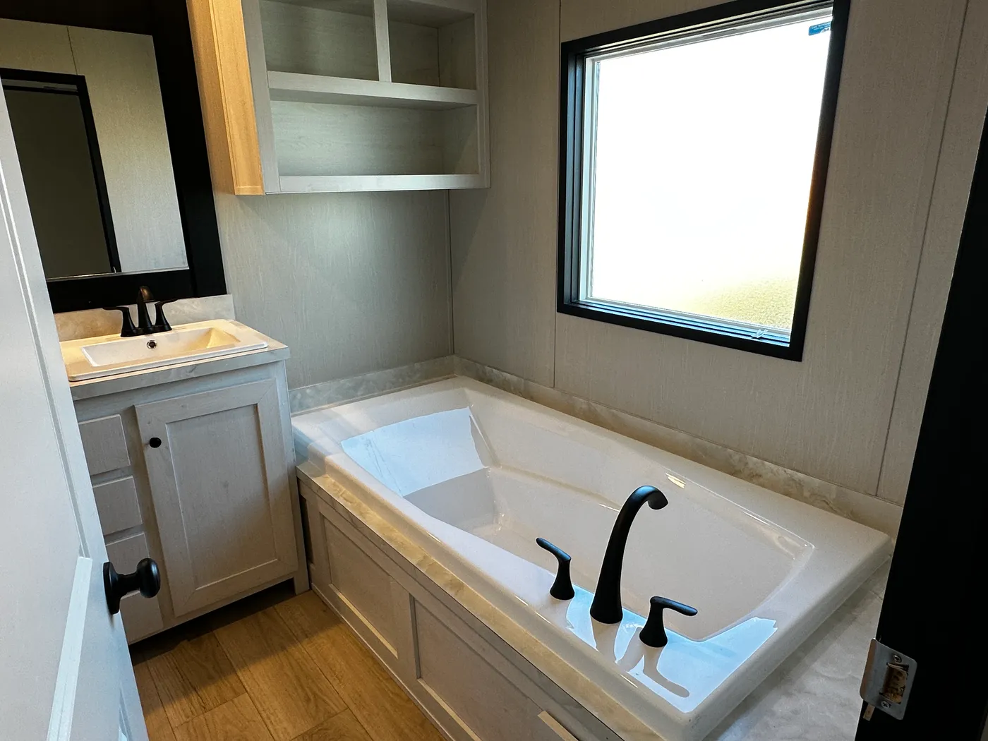 Beautiful 3 bedroom, 2 bathroom manufactured home featuring a modern charcoal interior and open-concept design. The stylish kitchen includes stainless steel appliances, a stainless steel farmhouse sink, and ample cabinet space. The spacious living room offers a built-in entertainment center with electric fireplace, perfect for relaxing or entertaining. The private primary suite features a tiled low-profile walk-in shower, a large garden soaking tub, and generous storage. This home combines affor