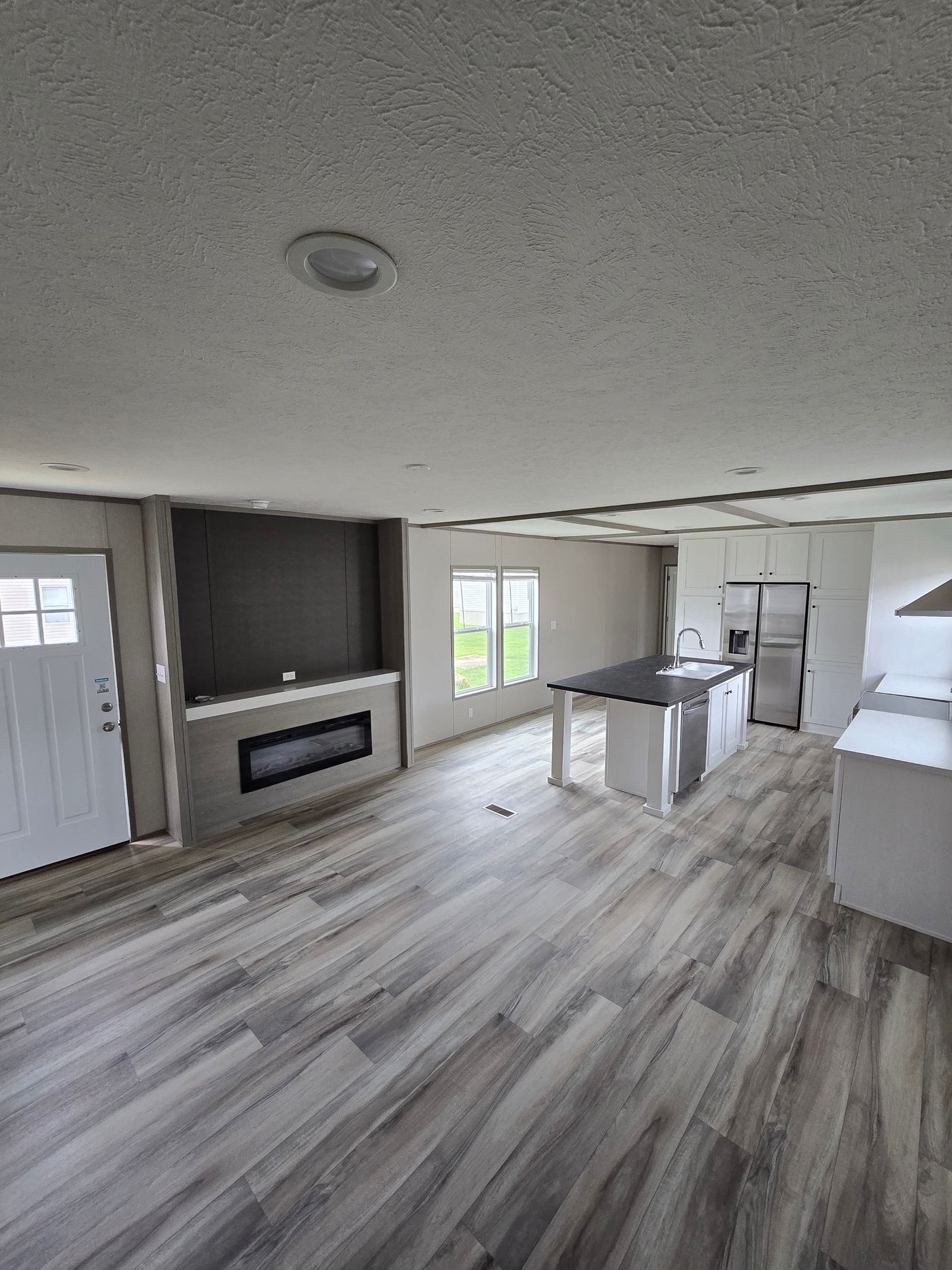From back of living room into kitchen showing entertainment center and electric fireplace