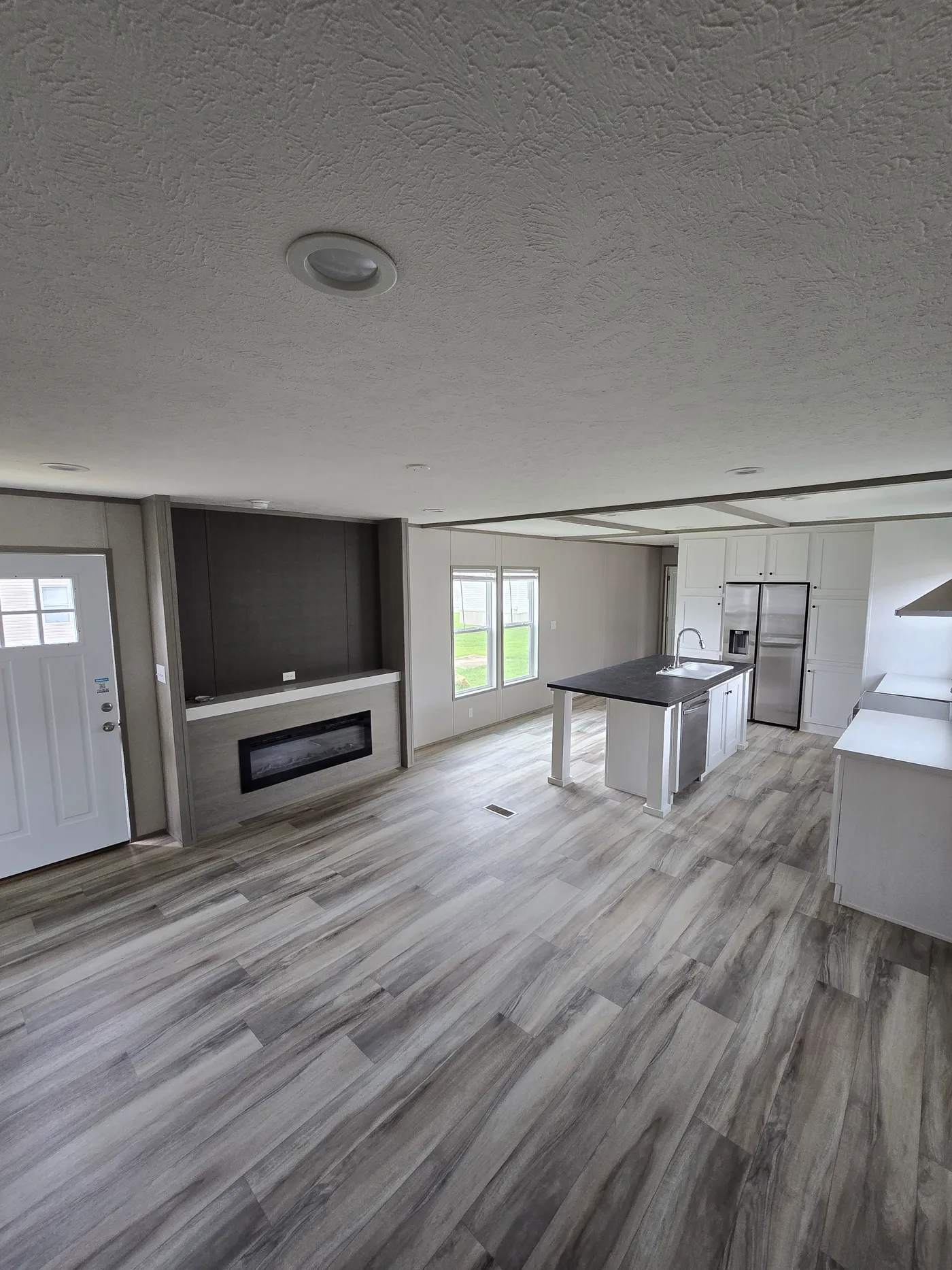 From back of living room into kitchen showing entertainment center and electric fireplace
