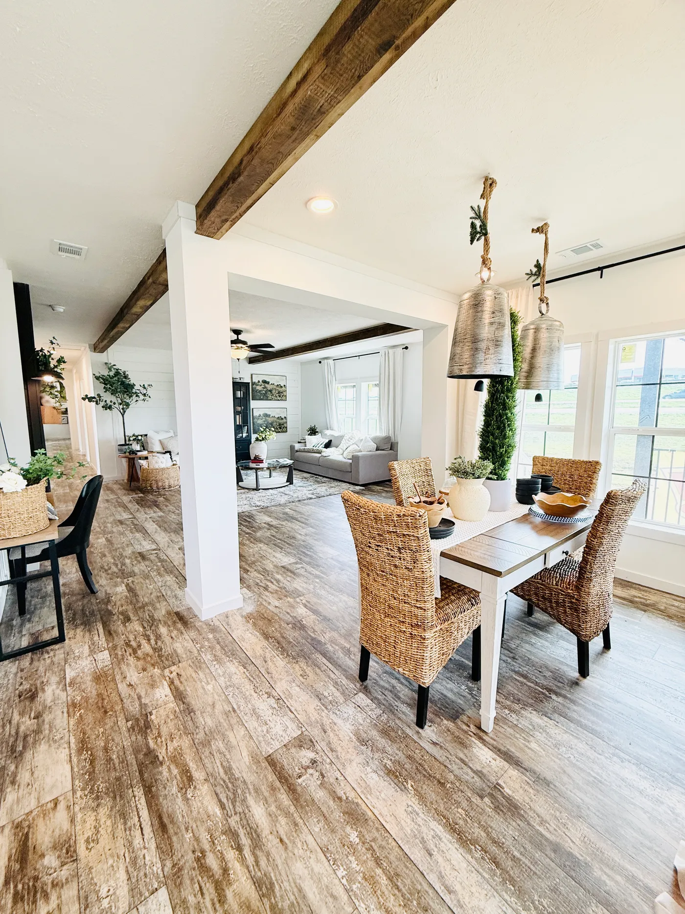 This charming dining area offers the perfect place to gather and enjoy meals while overlooking the spacious open-concept living area. Large windows provide beautiful natural light, highlighting the warm wood tones, exposed beams, and stylish finishes throughout the home. The layout flows seamlessly into the living room and kitchen, creating an inviting space ideal for entertaining or everyday living.