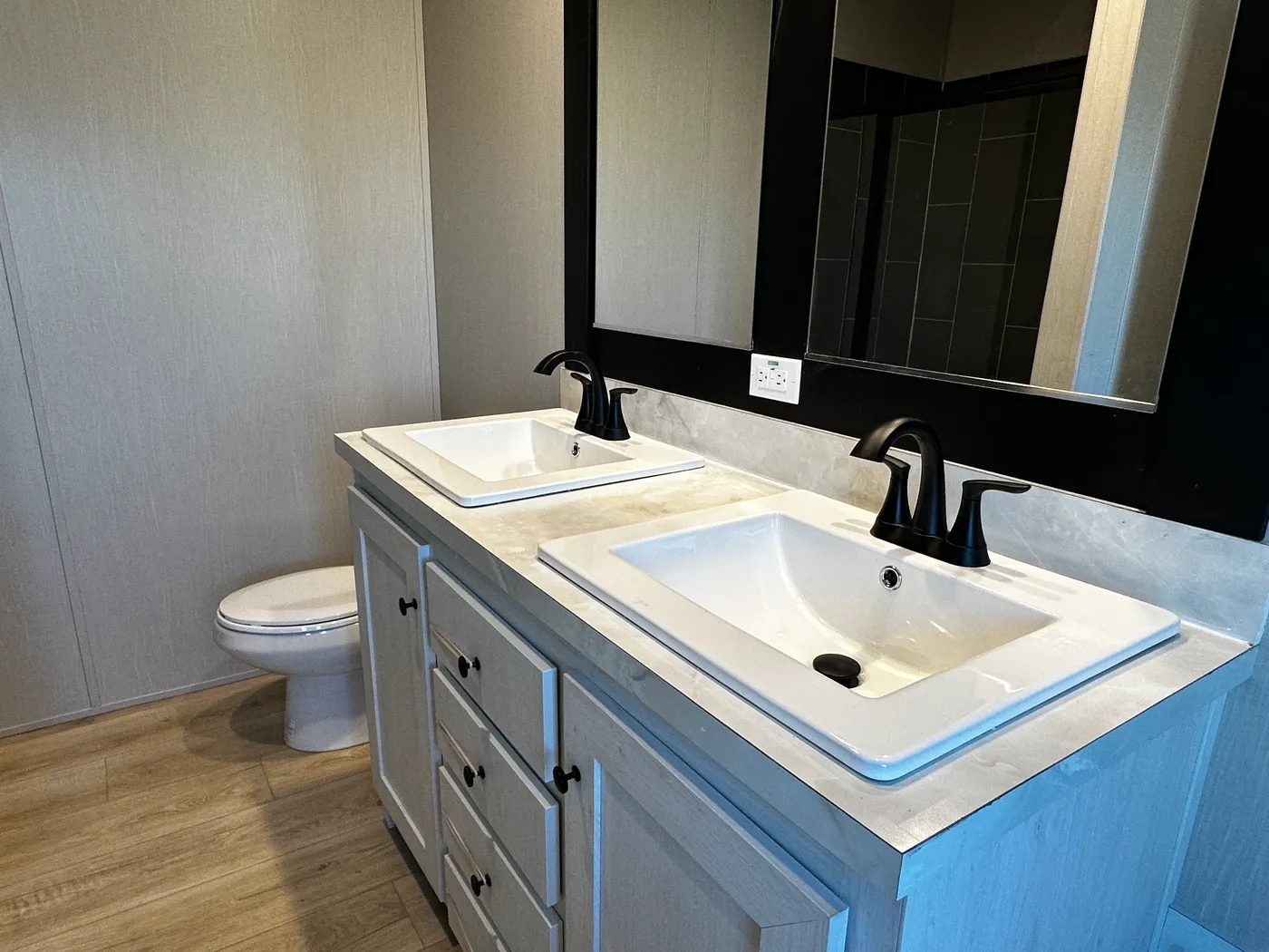 Beautiful 3 bedroom, 2 bathroom manufactured home featuring a modern charcoal interior and open-concept design. The stylish kitchen includes stainless steel appliances, a stainless steel farmhouse sink, and ample cabinet space. The spacious living room offers a built-in entertainment center with electric fireplace, perfect for relaxing or entertaining. The private primary suite features a tiled low-profile walk-in shower, a large garden soaking tub, and generous storage. This home combines affor