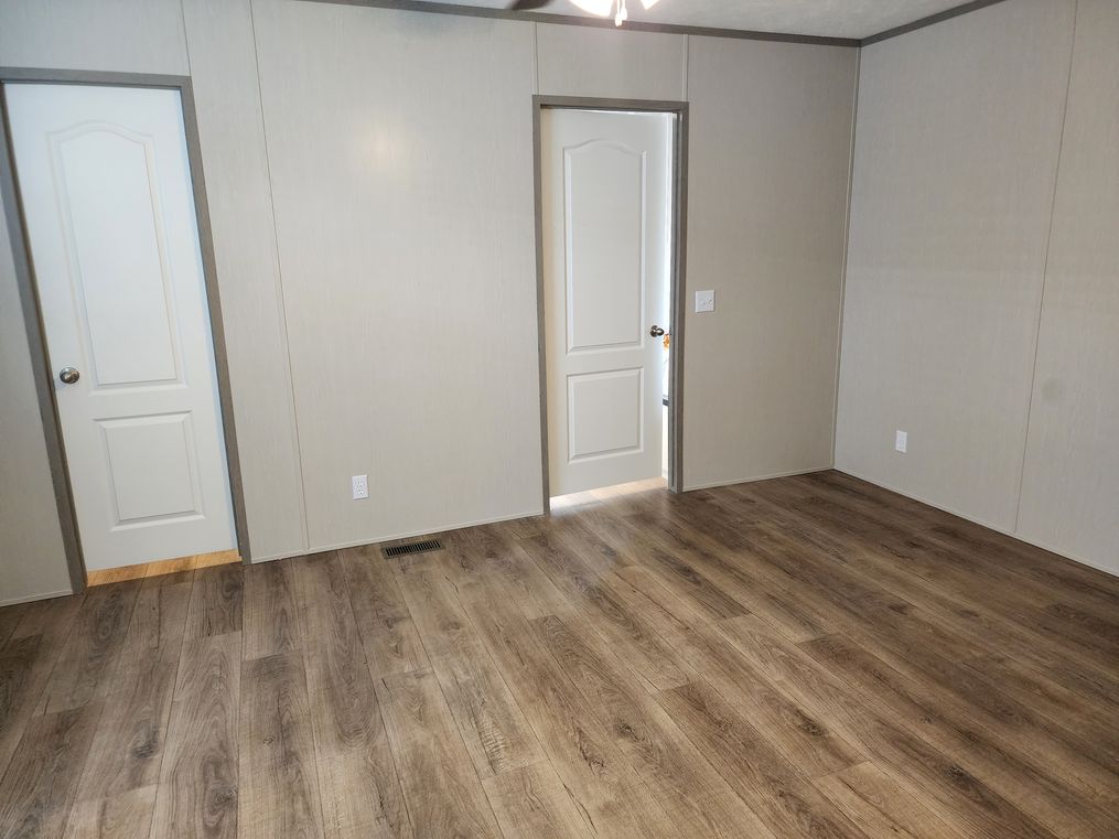 Primary bedroom with vinyl flooring and a walk in closet