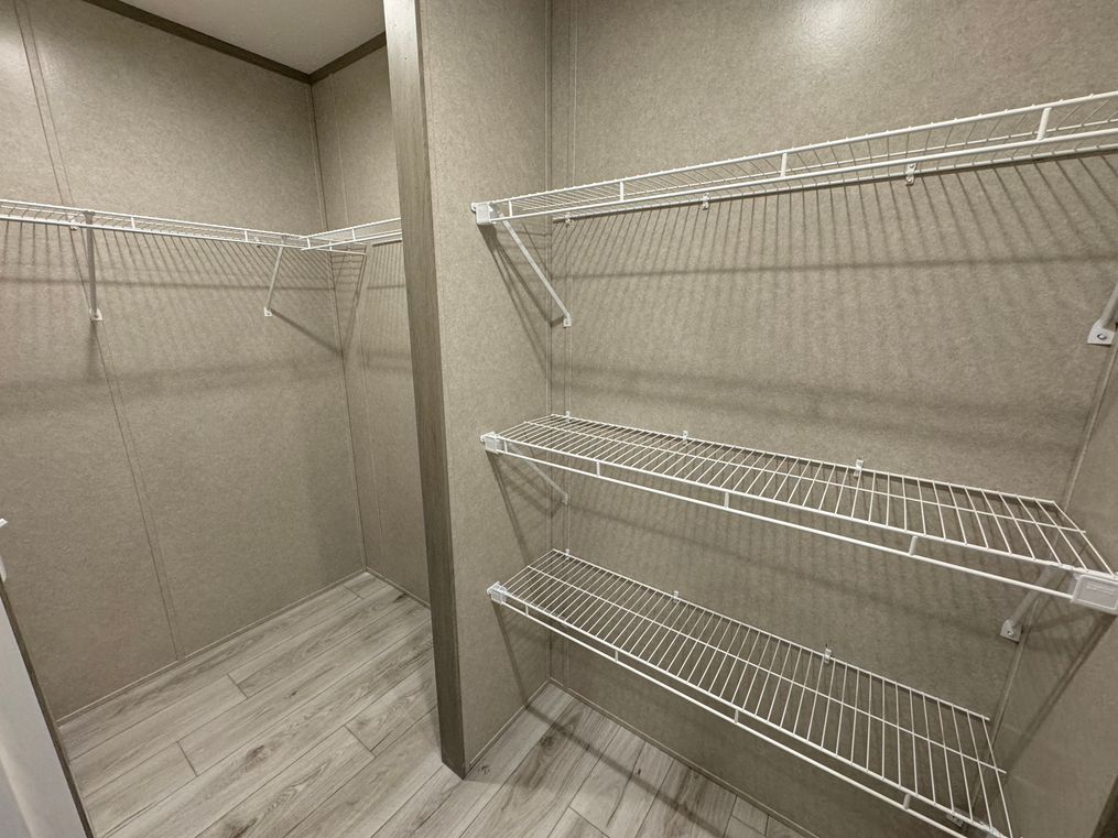 Primary his and hers closet with large shared shelf space in the middle 