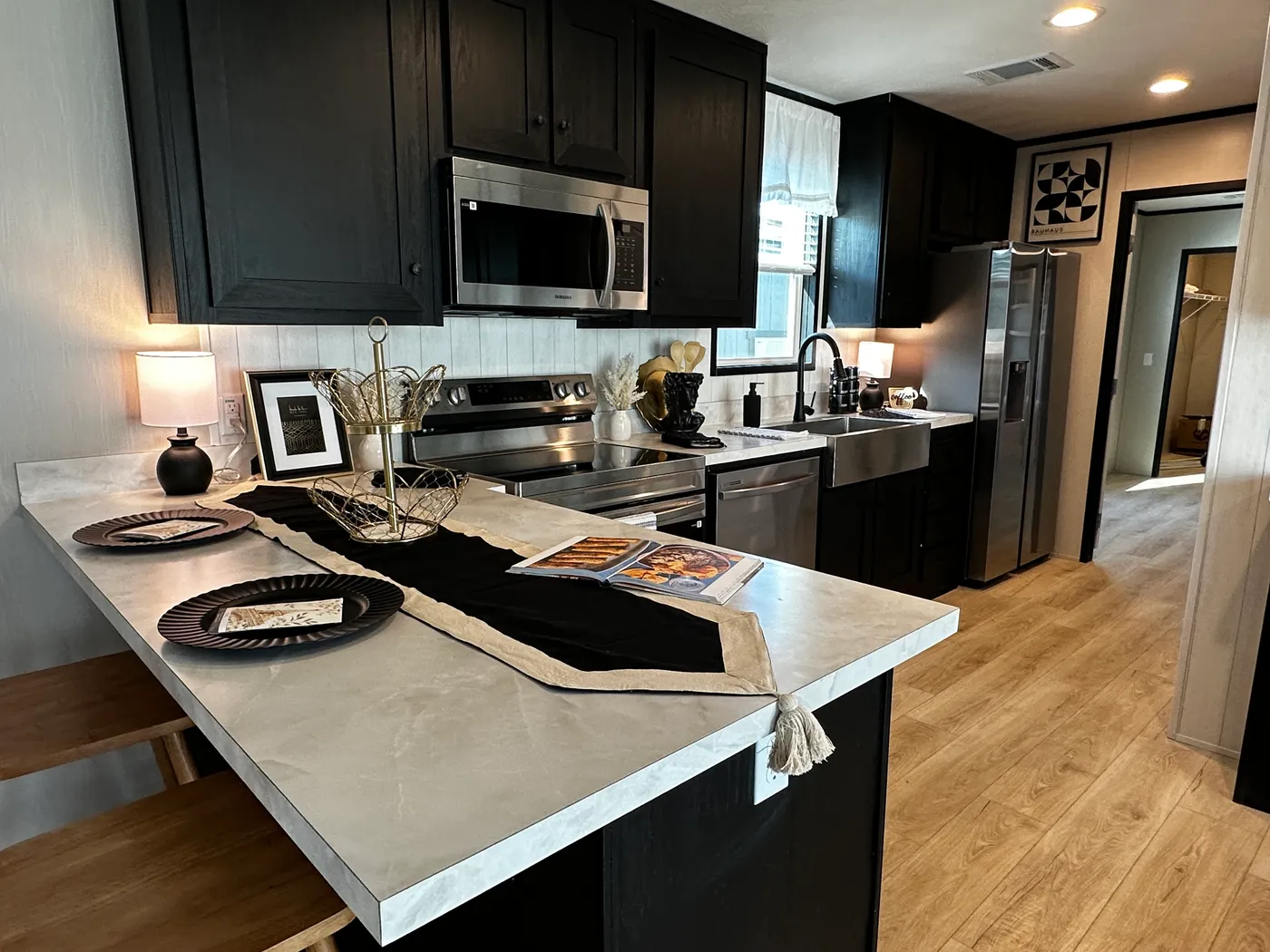 Beautiful 3 bedroom, 2 bathroom manufactured home featuring a modern charcoal interior and open-concept design. The stylish kitchen includes stainless steel appliances, a stainless steel farmhouse sink, and ample cabinet space. The spacious living room offers a built-in entertainment center with electric fireplace, perfect for relaxing or entertaining. The private primary suite features a tiled low-profile walk-in shower, a large garden soaking tub, and generous storage. This home combines affor