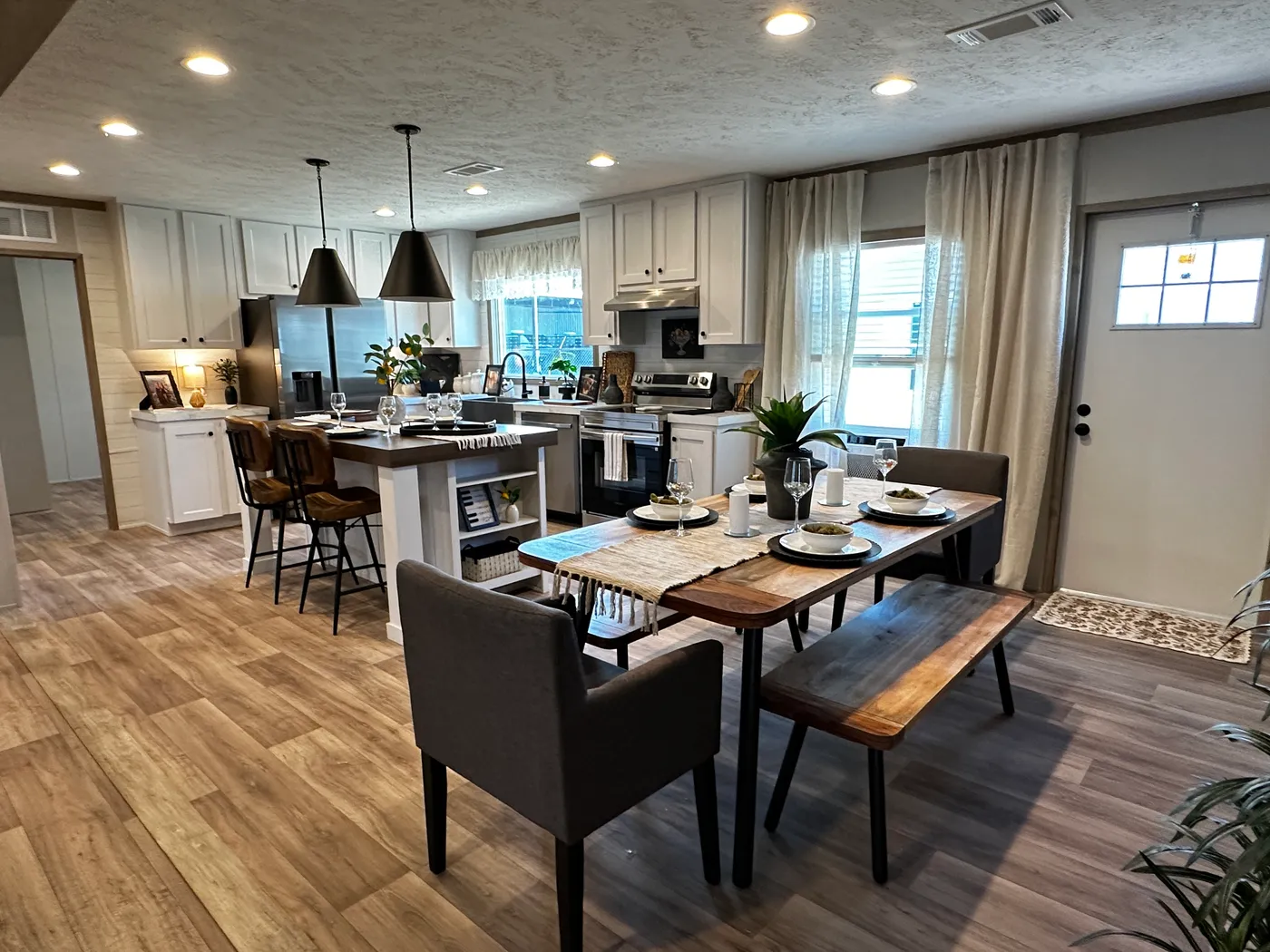 Modern luxury meets affordability in this 3 bedroom, 2 bathroom double wide manufactured home designed for comfort and style. The open-concept layout features a spacious living area with a gorgeous built-in entertainment center and plenty of natural light. The designer kitchen includes stainless steel appliances, a large kitchen island, and ample cabinet space, perfect for cooking and entertaining. Enjoy enhanced comfort with energy-efficient upflow ceiling vents for improved airflow throughout 