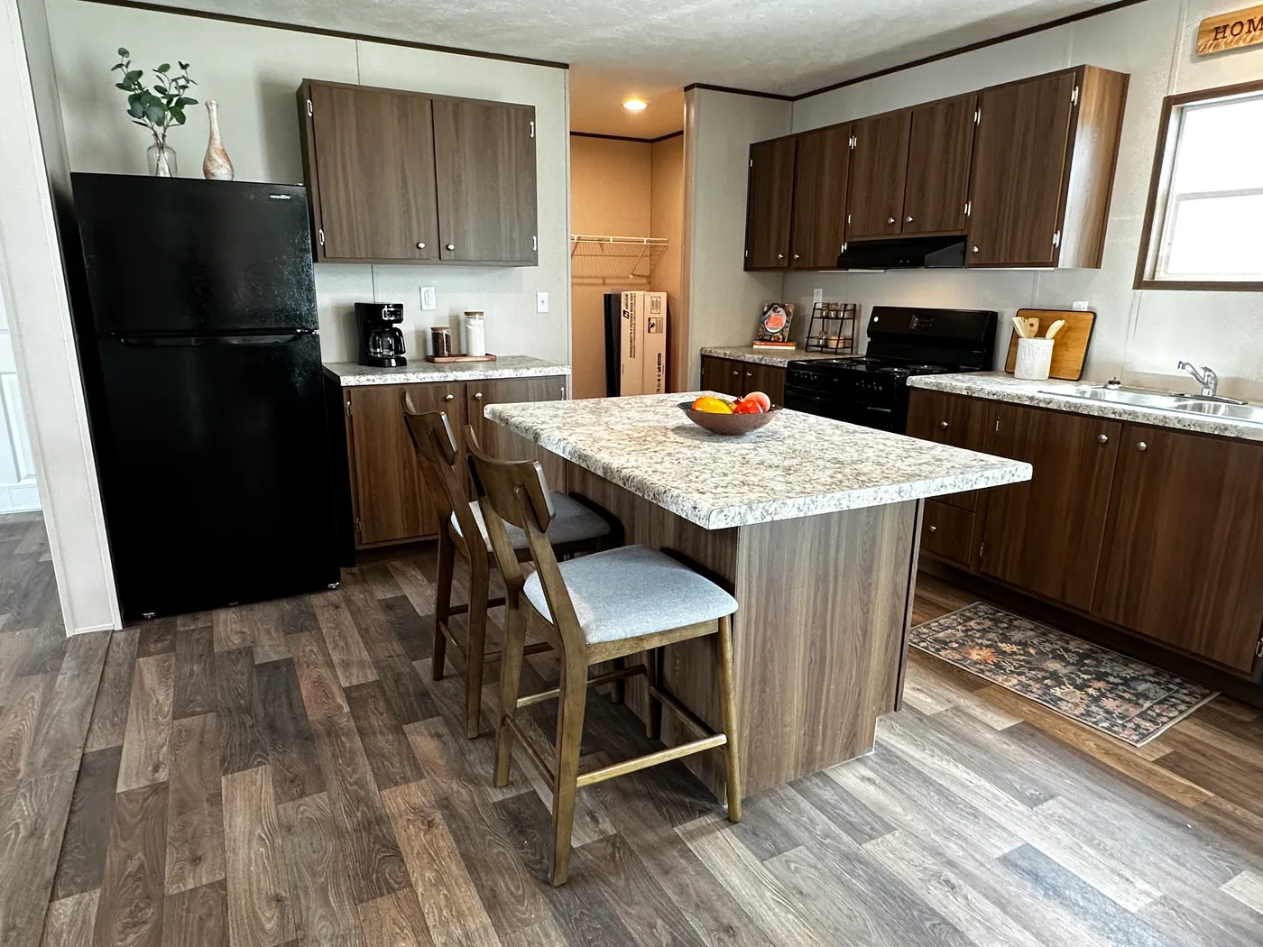 Discover the most affordable and spacious 4 bedroom, 2 bath doublewide manufactured home on the market! This budget-friendly mobile home features elevated ceilings, an open-concept layout, and plenty of room to grow with both a living room and separate den—perfect for entertaining, relaxing, or family space. The modern kitchen includes a large center island with ample storage and workspace. The private primary suite offers a walk-in closet, plus a luxury separate soaking tub and walk-in shower f