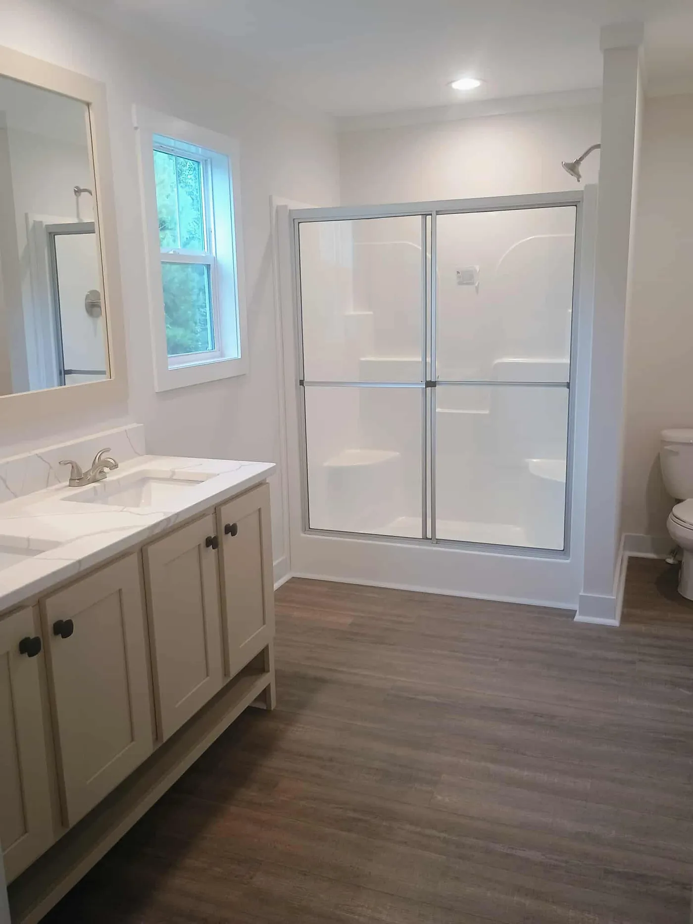 Primary bathroom with double vanity and standup shower with LVP flooring 